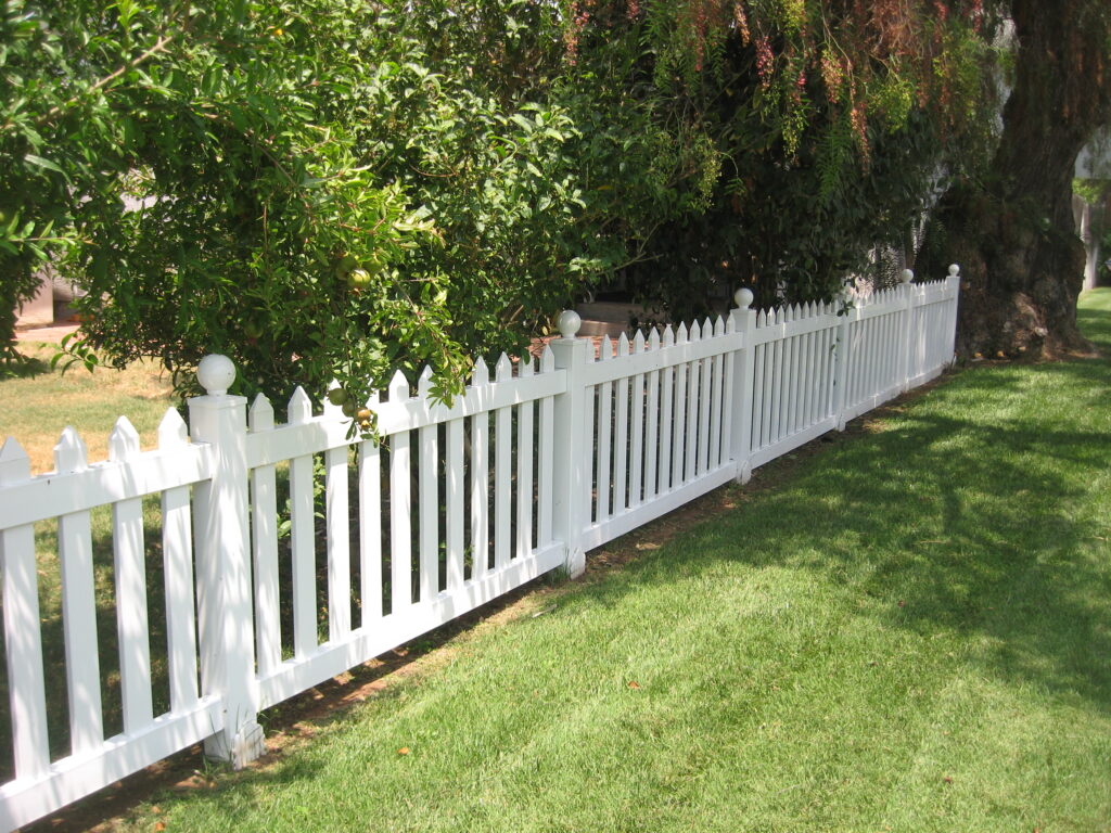 Pointed tops and ball caps on vinyl picket fence by Alpine Fence Company.