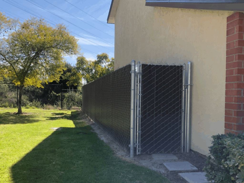 95% brown vinyl slats over a chain-link fence by Alpine Fence Company.