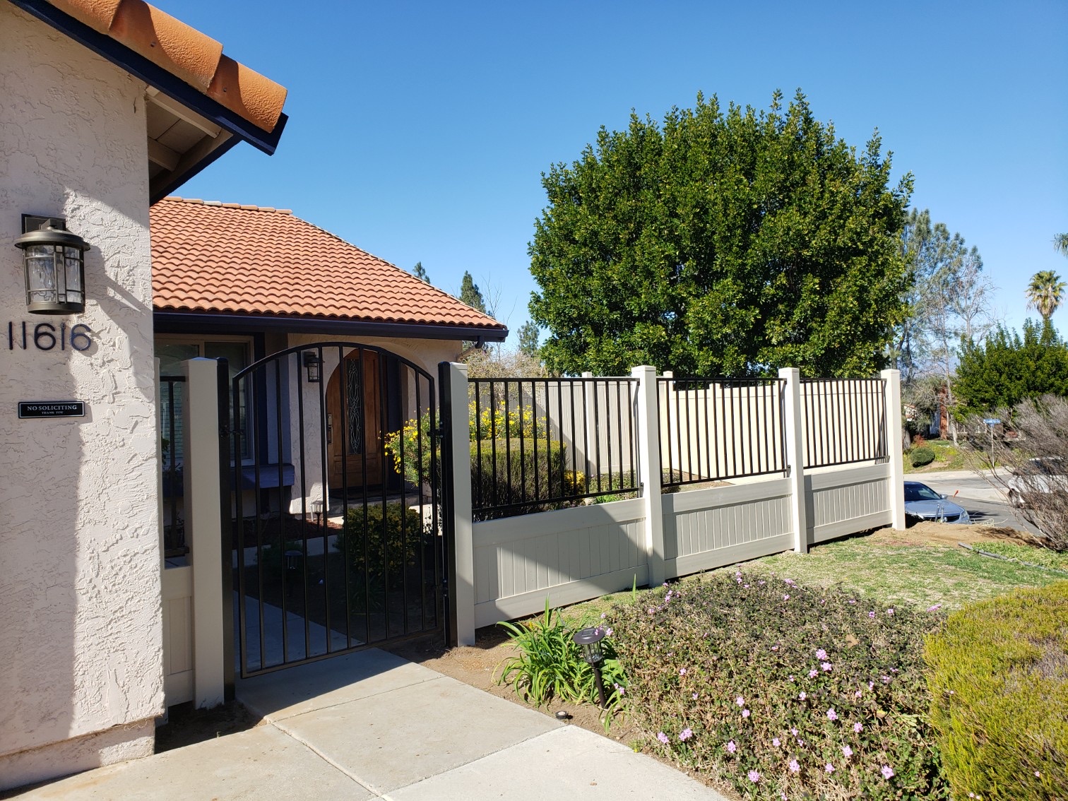 Privacy vinyl fence with iron top and gate by Alpine Fence Company.