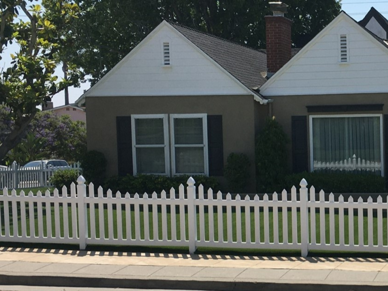 Scalloped vinyl picket fence with gothic caps by Alpine Fence Company.