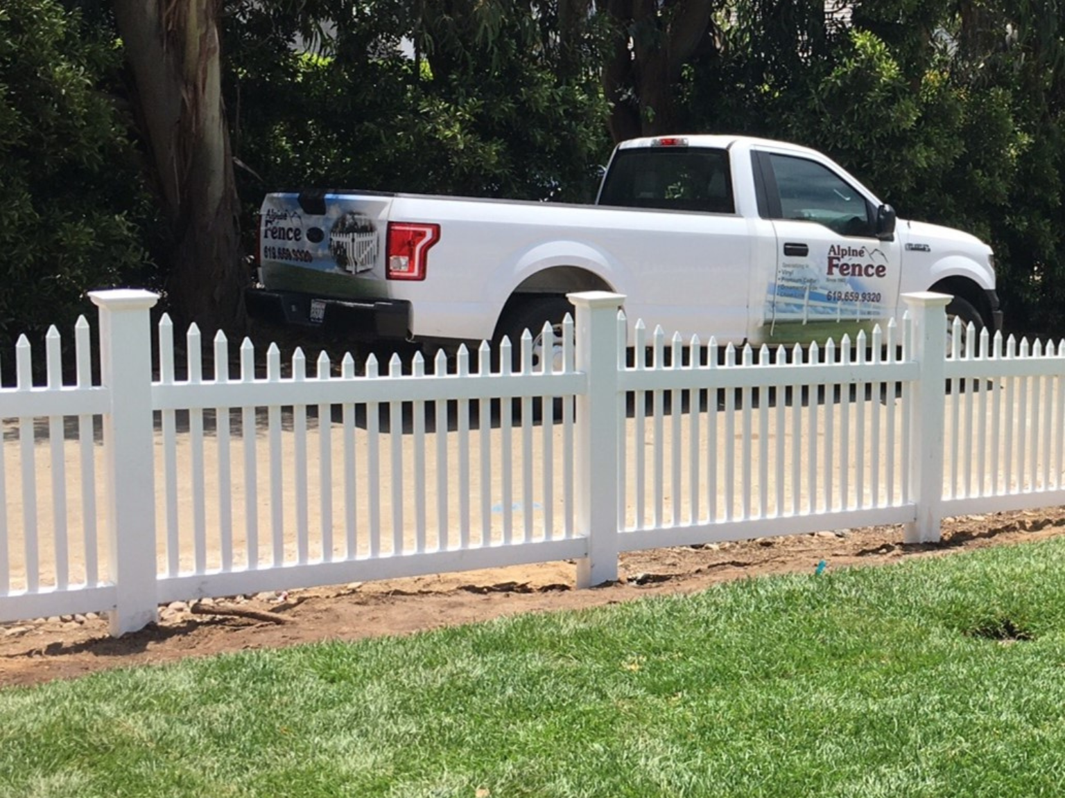 Scalloped narrow vinyl picket fence by Alpine Fence Company.