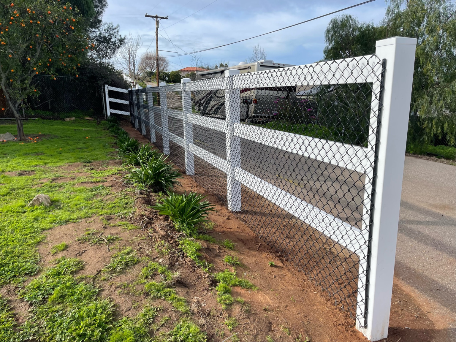 Vinyl ranch rail with black chain link backing by Alpine Fence Company.