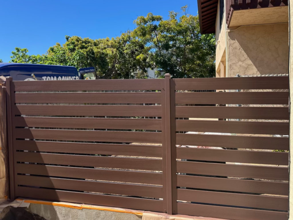 12. Brown metal semi-privacy fence with horizontal slats in a residential yard.