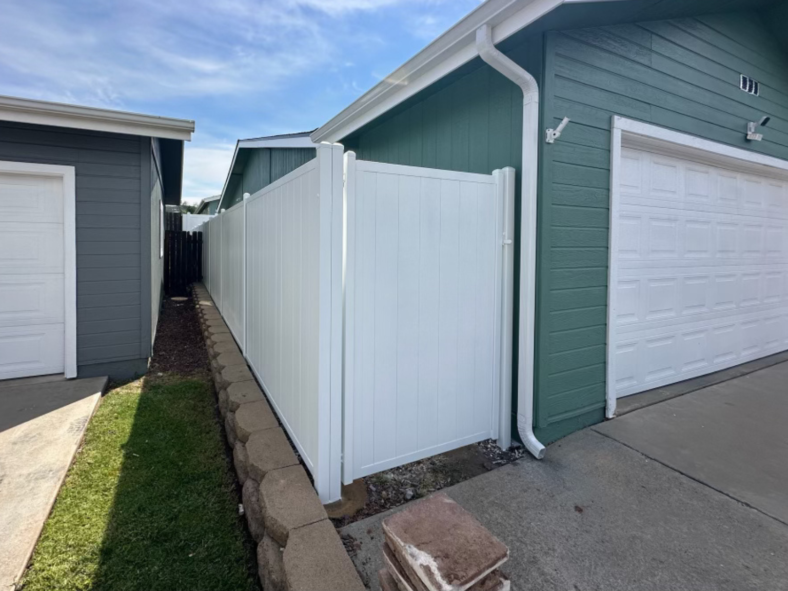 4. White vertical full privacy metal fence on the side of a home.